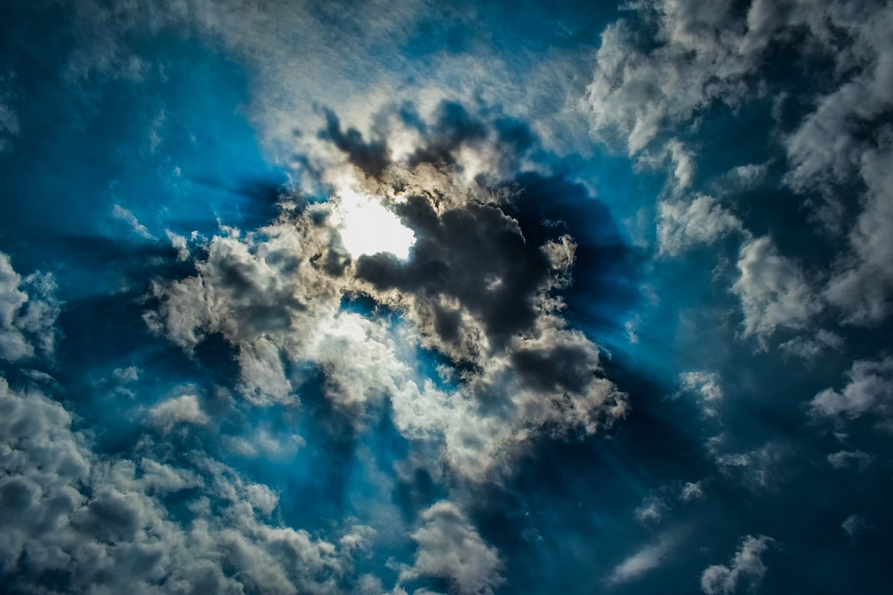 blue sky and clouds covering the sun